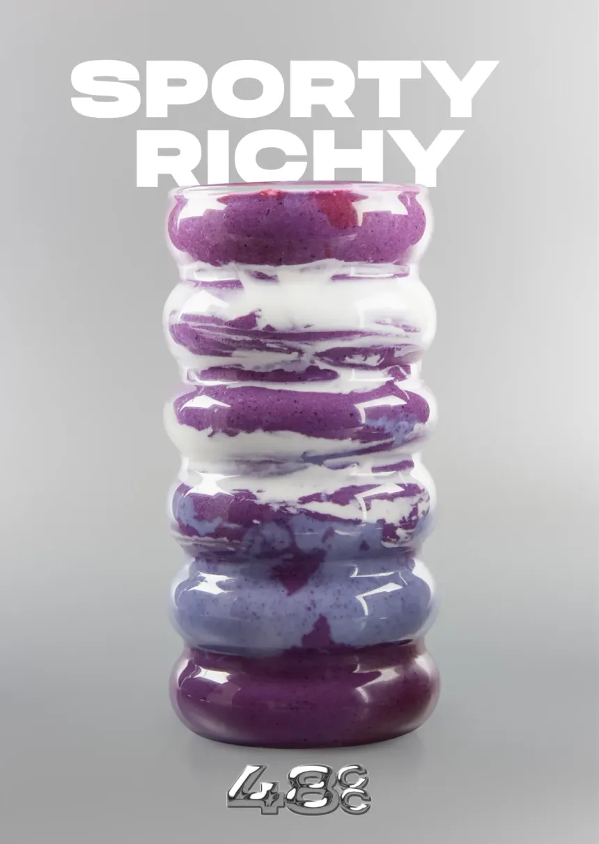 El batido Sporty & Richy del café de colágeno de Vernal: un vaso violeta de arándano servido en una copa ondulada